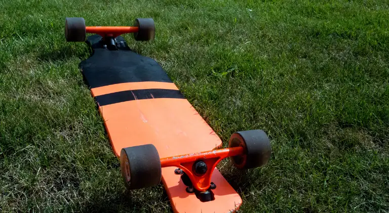 A longboard upside down laying in the grass